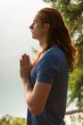 Close-up of fit man standing in meditating posture on the edge of the rock — Stock Photo