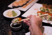 Homem mergulhando sushi em molho de soja em um restaurante — Fotografia de Stock