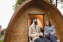 Happy couple having coffee outside the log cabin — Stock Photo