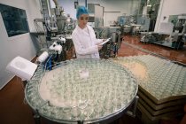 Жінка-працівник контролює скляні банки на виробничій лінії на заводі — стокове фото