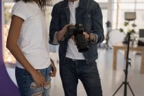 Mid section of photographer showing photos to fashion model on digital camera — Stock Photo