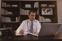 Determined doctor working and writing in book in office. — Stock Photo