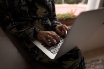 Partie médiane de la femme musulmane utilisant un ordinateur portable à la maison — Photo de stock