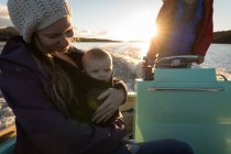 Mãe com bebê e pai viajando em barco a motor durante o pôr do sol . — Fotografia de Stock