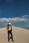 Escursionista femminile con zaino in piedi sulla sabbia in una giornata di sole — Foto stock