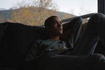 Hombre joven relajándose en la sala de estar en casa - foto de stock