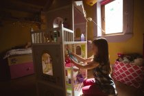 Mädchen spielt mit Puppenhaus im Schlafzimmer zu Hause — Stockfoto
