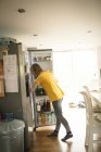 Mujer en cocina buscando en nevera en casa - foto de stock