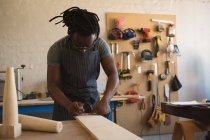Плотник измеряет деревянную доску в мастерской — стоковое фото