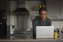 Молодой человек использует ноутбук дома — стоковое фото