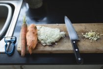 Gehacktes Gemüse mit Messer auf Schneidebrett in Küche — Stockfoto
