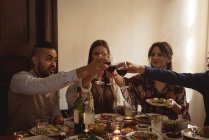 Freunde stoßen beim Essen am Tisch auf Wein an — Stockfoto