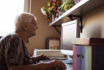 Старша жінка працює на комп'ютері в будинку престарілих — стокове фото