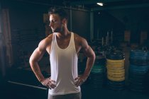 Решительный мускулистый человек, стоящий с руками на бедре в фитнес-студии — стоковое фото