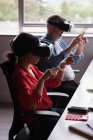 Colegas experimentando fone de ouvido de realidade virtual na mesa no escritório criativo — Fotografia de Stock