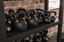 Close-up of kettlebells on shelf in fitness studio. — Stock Photo