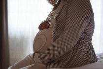 Вид сбоку на беременную женщину, трогающую живот — стоковое фото