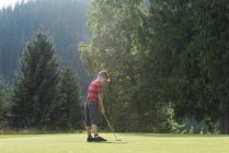 Joven caucásico niño jugando al golf en el campo - foto de stock