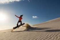 Mulher sandboard na duna de areia em um dia ensolarado — Fotografia de Stock