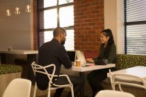 Compañeros de negocios que interactúan entre sí en la cafetería de la oficina - foto de stock