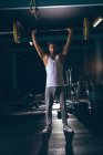 Retrato de homem musculoso exercitando com barbell no estúdio de fitness — Fotografia de Stock