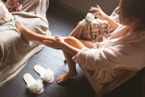 Mujer aplicando crema en las piernas en el dormitorio en casa . - foto de stock