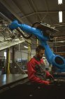 Travailleur masculin vérifiant une pièce de machine dans l'usine — Photo de stock