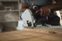 Mid section of carpenter leveling wood in workshop — Stock Photo