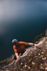 Скалолаз достигает вершины скалы в солнечный день — стоковое фото
