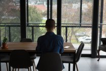 Vue arrière de l'homme assis sur une chaise à la maison — Photo de stock