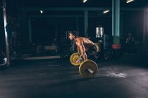 Uomo muscolare che si allena con il bilanciere nella sala fitness — Foto stock