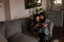 Mãe e filha muçulmana usando tablet digital em casa — Fotografia de Stock