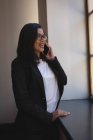 Business woman talking on mobile phone near window at office. — Stock Photo