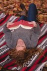 Bella donna sdraiata nel parco autunnale e leggere romanzo — Foto stock
