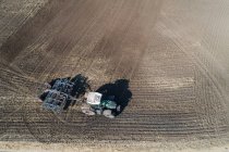 Aerial of tractor plowing the field on a sunny day — Stock Photo