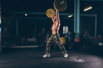 Muscular man exercising with barbell in the fitness studio — Stock Photo