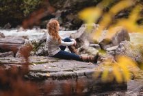 Red head Woman sitting on the river coast — Stock Photo