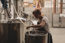 Trabajador llenando bebida alcohólica en tambor en fábrica - foto de stock