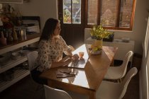 Donna caucasica che utilizza il computer portatile a tavola a casa — Foto stock