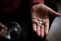 Крупный план руки пожилой женщины, принимающей лекарства — стоковое фото