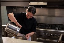 Koch gießt Öl in Behälter in Großküche — Stockfoto
