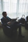 Geschäftsmann liest Zeitung auf Sessel im Hotel — Stockfoto