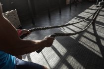 Cropped view of man doing cross fit rope training in fitness studio. — Stock Photo