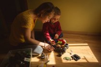 Madre e figlio riparazione auto giocattolo in camera da letto a casa — Foto stock