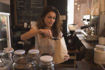 Serveuse emballant des aliments sucrés dans un sac en papier au comptoir dans un café — Photo de stock
