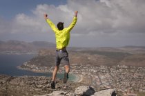 Escursionista che salta sulla vetta della montagna in una giornata di sole — Foto stock