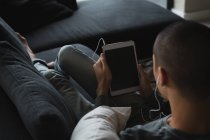 Молодий чоловік слухає музику на цифровому планшеті у вітальні вдома — стокове фото