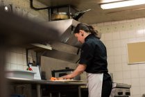 Konzentrierter Koch hackt Gemüse in der Großküche — Stockfoto