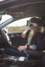 Vista laterale del dirigente femminile utilizzando cuffie realtà virtuale in una macchina — Foto stock