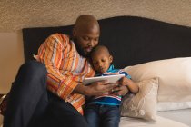 Father and son using digital tablet in bedroom at home. — Stock Photo